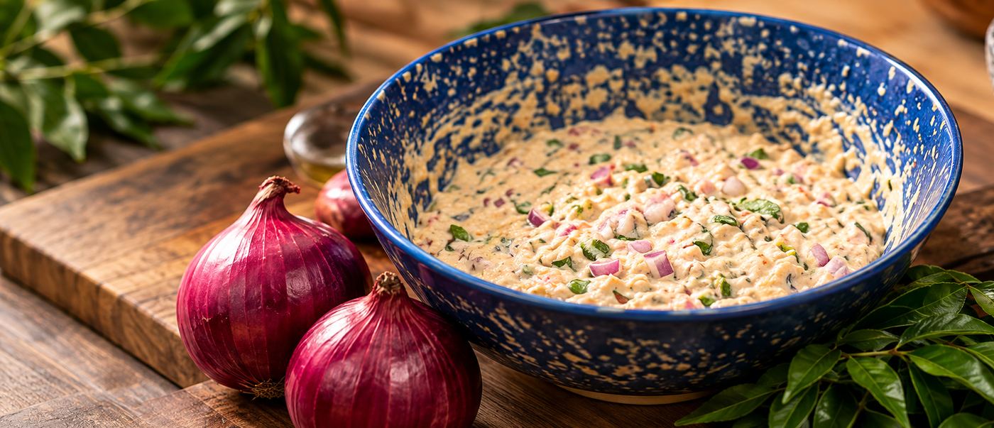 A bowl of vadai batter with red onion and curry leaves